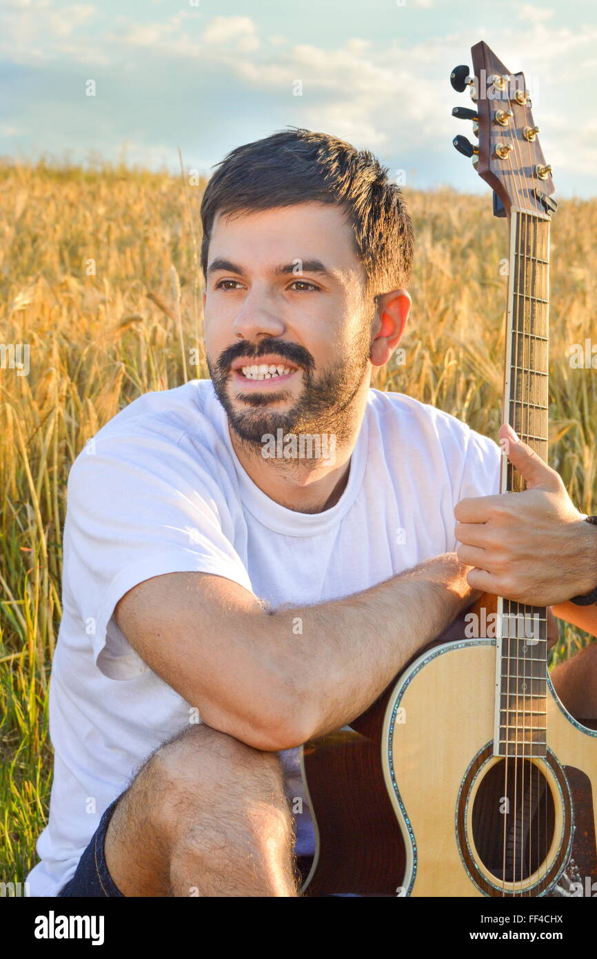 Ragazzo barbuto con una chitarra in campo thewheat Foto Stock