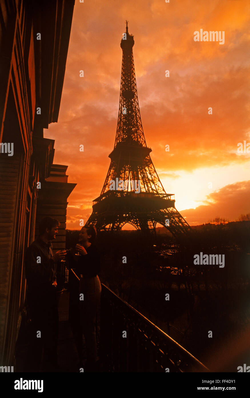 Coppia in appartamento balcone godersi il tramonto a bere sotto il cielo drammatico vicino alla Torre Eiffel a Parigi Foto Stock