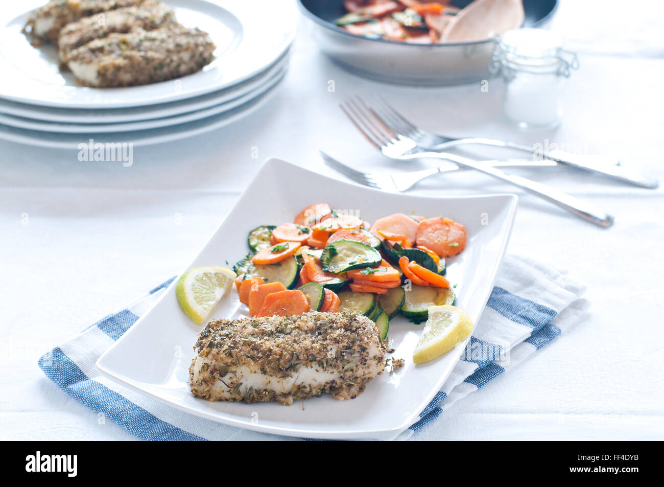 Merluzzo bianco con il piccante panatura servita con carote e zucchine Foto Stock
