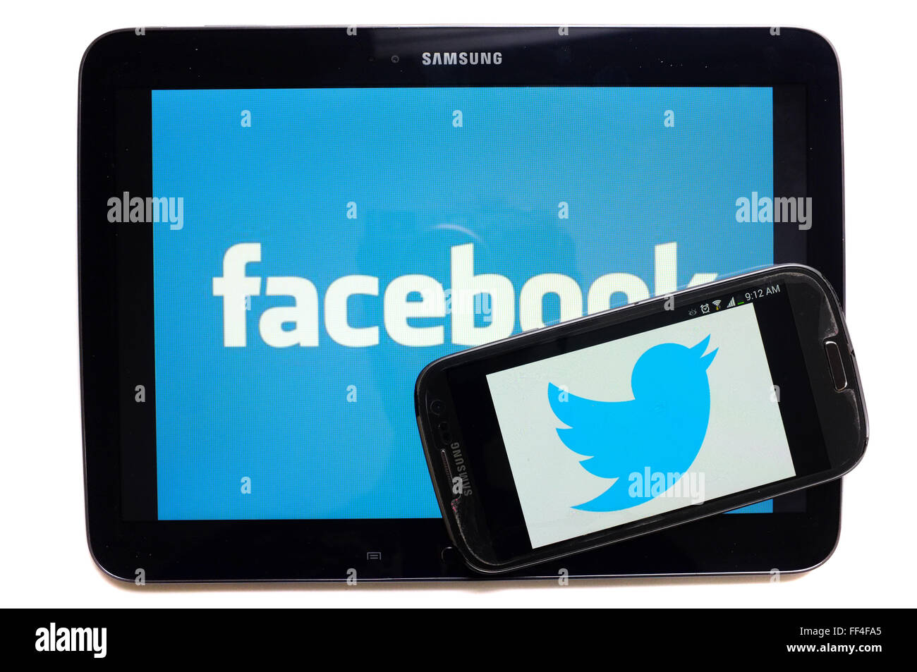 Il logo Twitter su uno smartphone e Facebook su un tablet fotografati contro uno sfondo bianco. Foto Stock