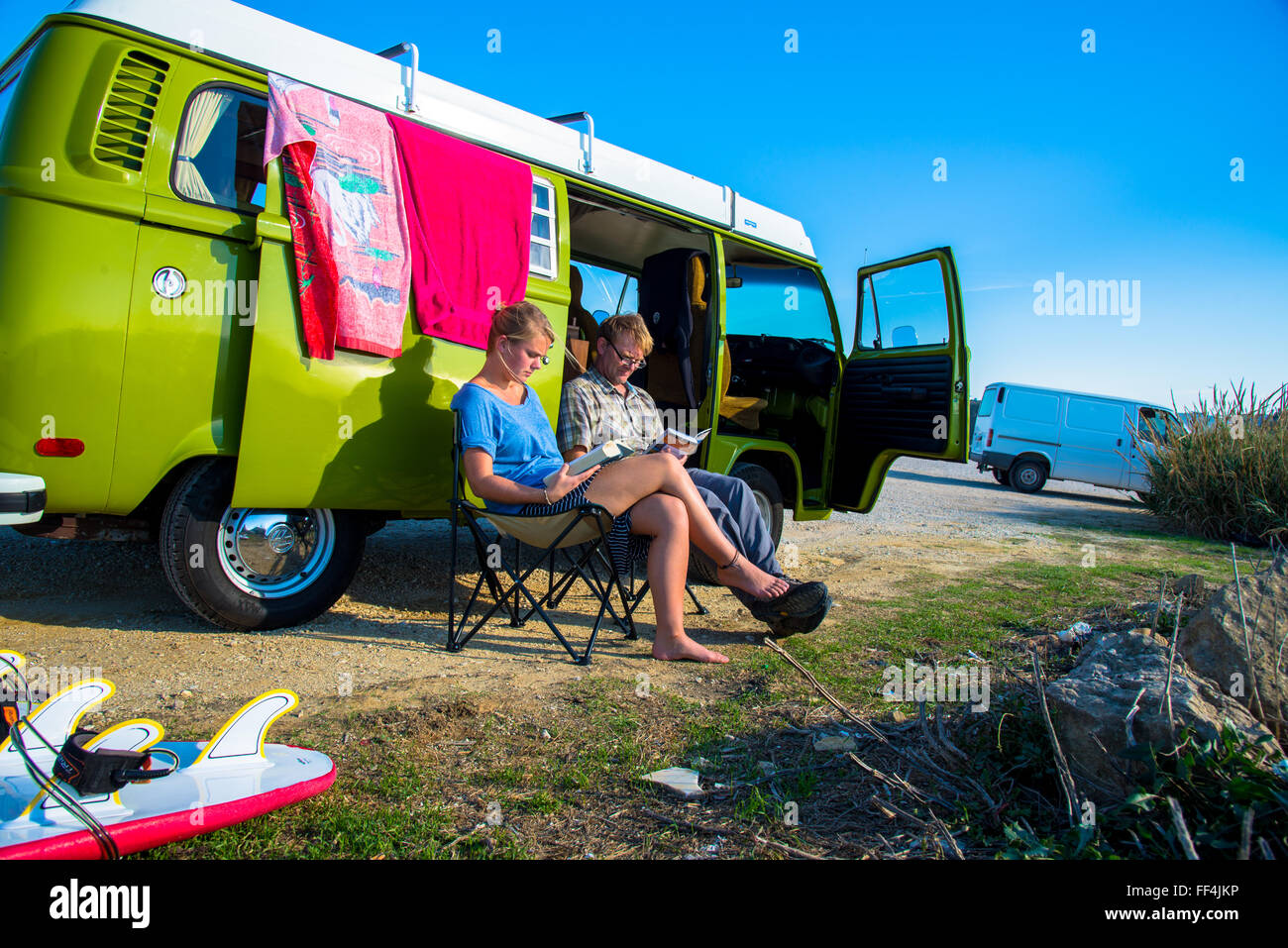 L uomo e la ragazza seduta e la lettura accanto a vw camper ericiera in Portogallo Foto Stock