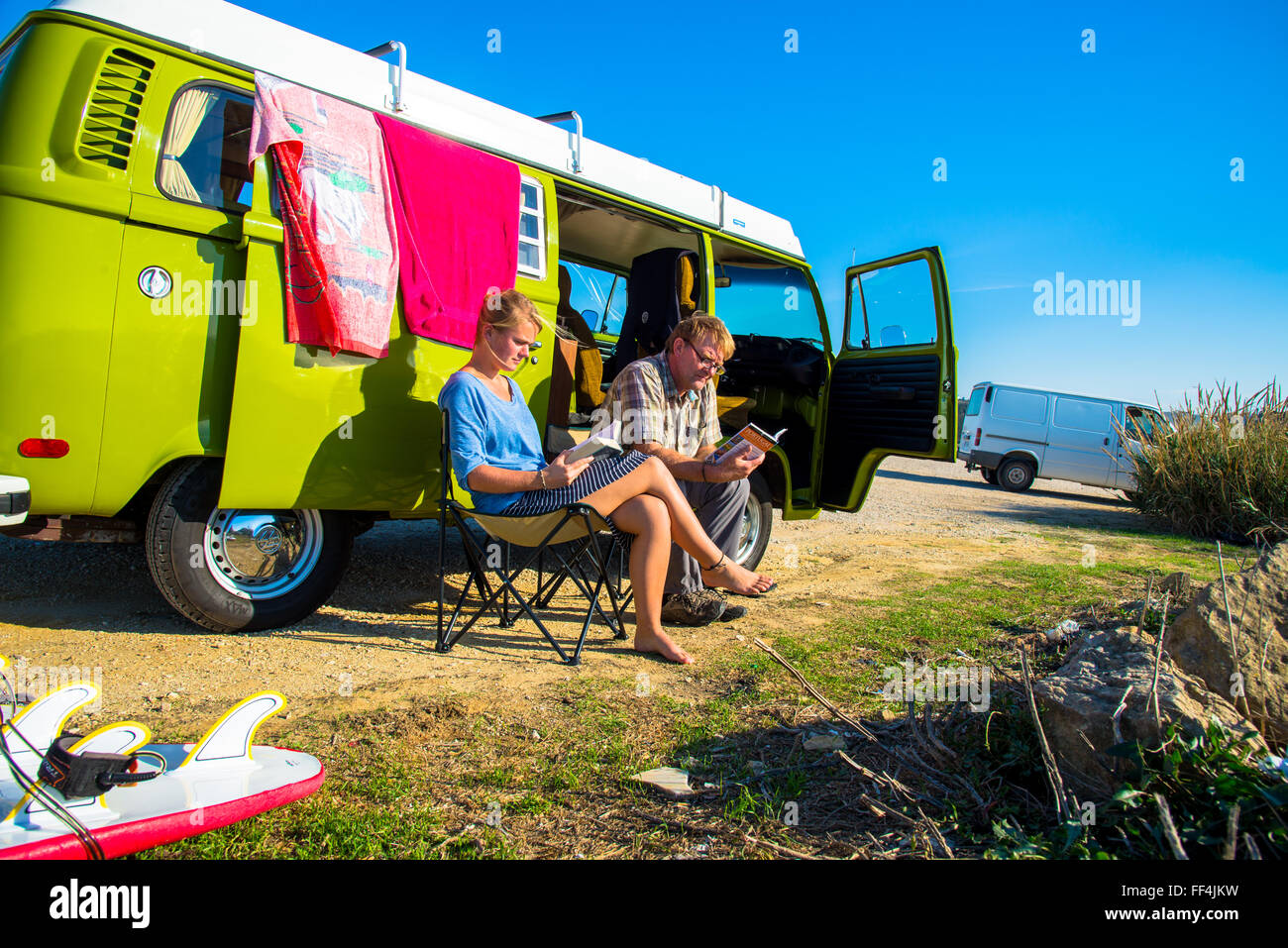L uomo e la ragazza seduta e la lettura accanto a vw camper ericiera in Portogallo Foto Stock