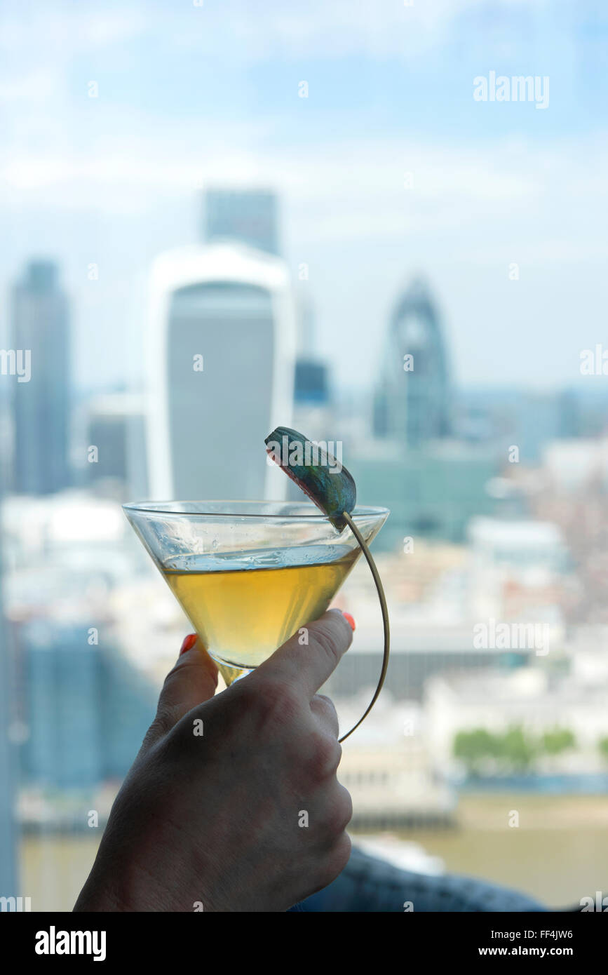 Un cocktail in un bicchiere da cocktail essendo aveva al Shard, con la città di Londra in background Foto Stock