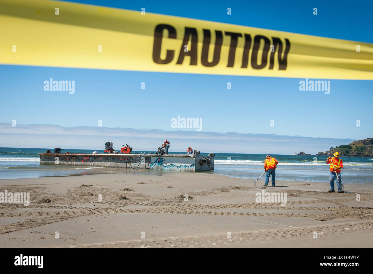 Lavoratori rimuovere un cemento floating boat dock che avevano deviato attraverso l'Oceano Pacifico risultante dal 2011 tsunami giapponese Foto Stock