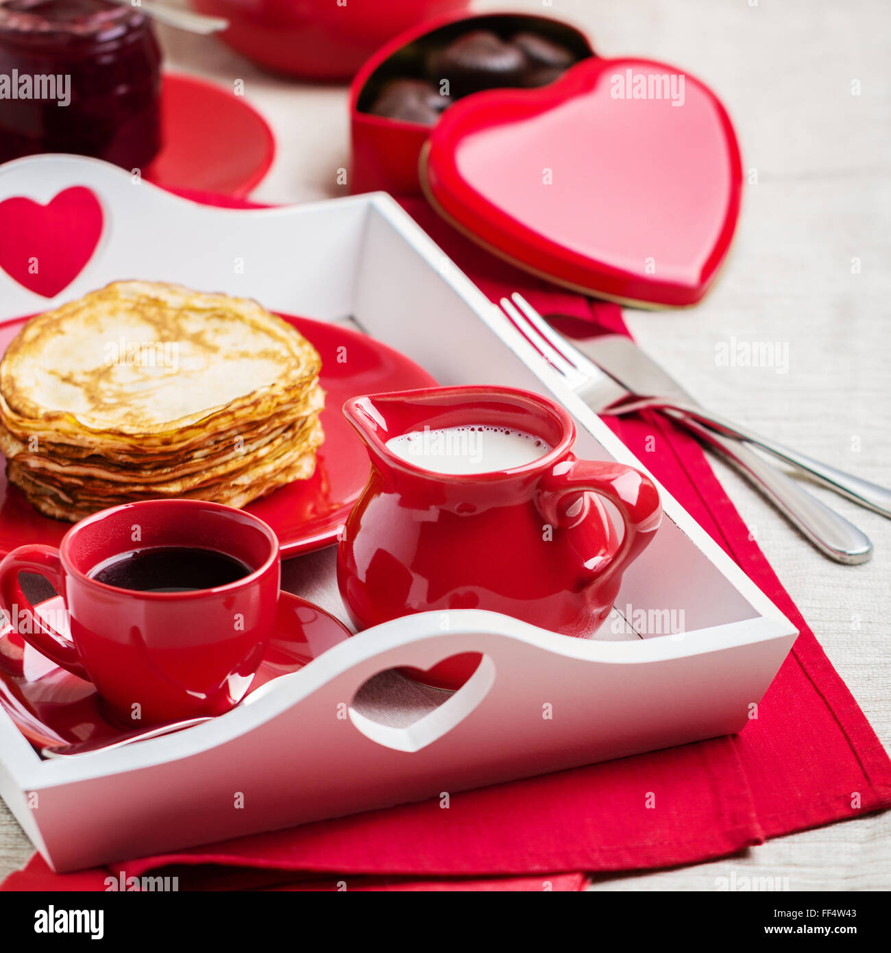La prima colazione. Frittelle e caffè con latte in un vassoio per il giorno di San Valentino. Messa a fuoco selettiva. Foto Stock