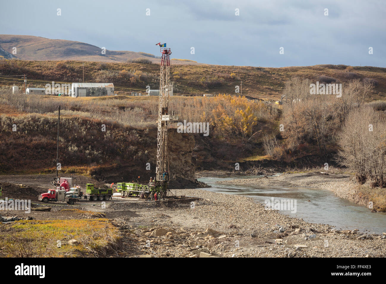 Un olio e gas service rig funziona su un lavato fuori wellsite lungo la riva del fiume Highwood nel sud dell'Alberta pedemontana Foto Stock