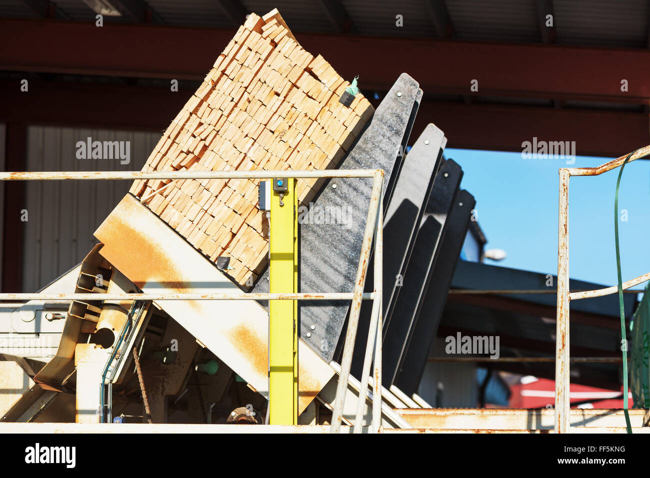 Una macchina che consente di decomprimere le pile di legname o tavole su un nastro trasportatore che passa in una fabbrica di fabbricazione. Foto Stock