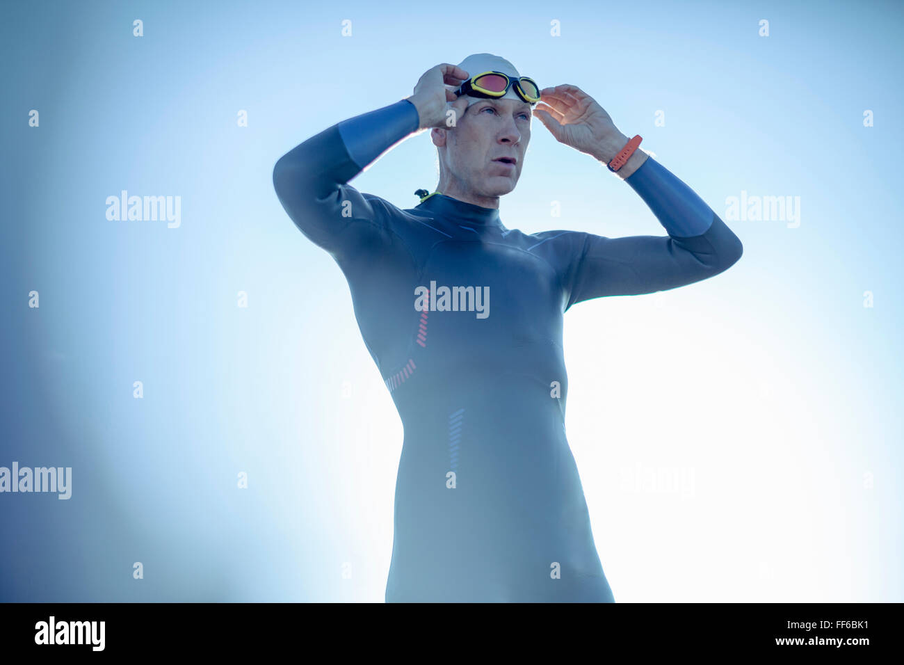 Un nuotatore in una muta e nuoto hat, regolando i suoi occhiali da nuoto. Foto Stock
