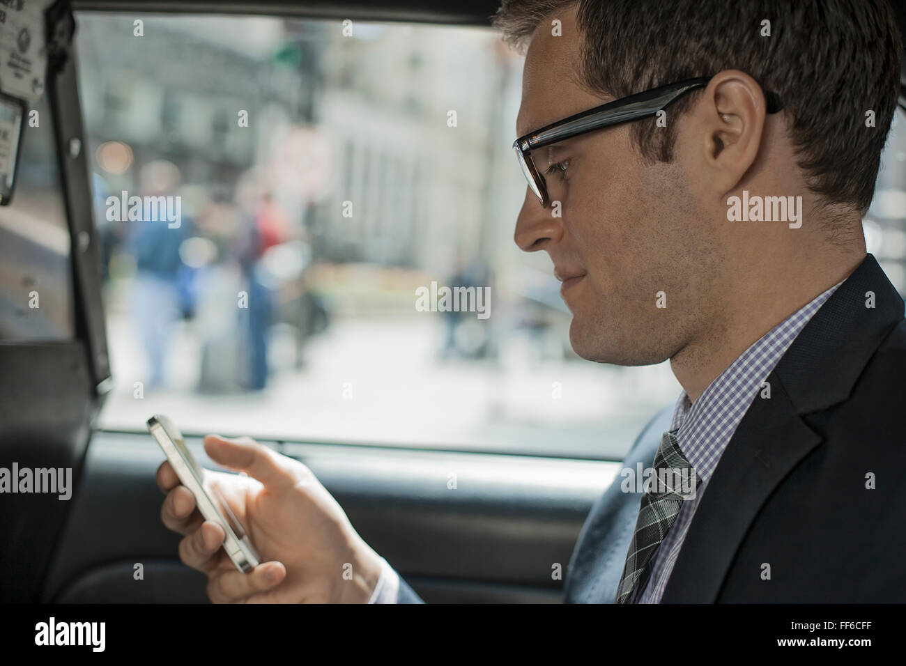 Una giornata di lavoro. Un uomo in un taxi giallo, utilizzando il suo smart phone. Foto Stock