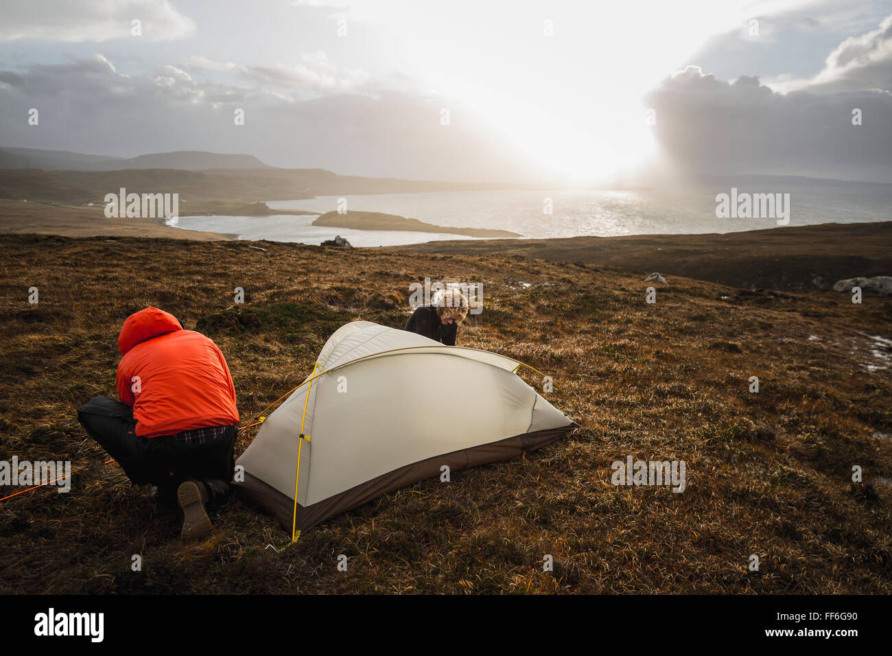 Due uomini che tengono e mettere una piccola tenda in spazio aperto. Campeggio selvaggio. Foto Stock