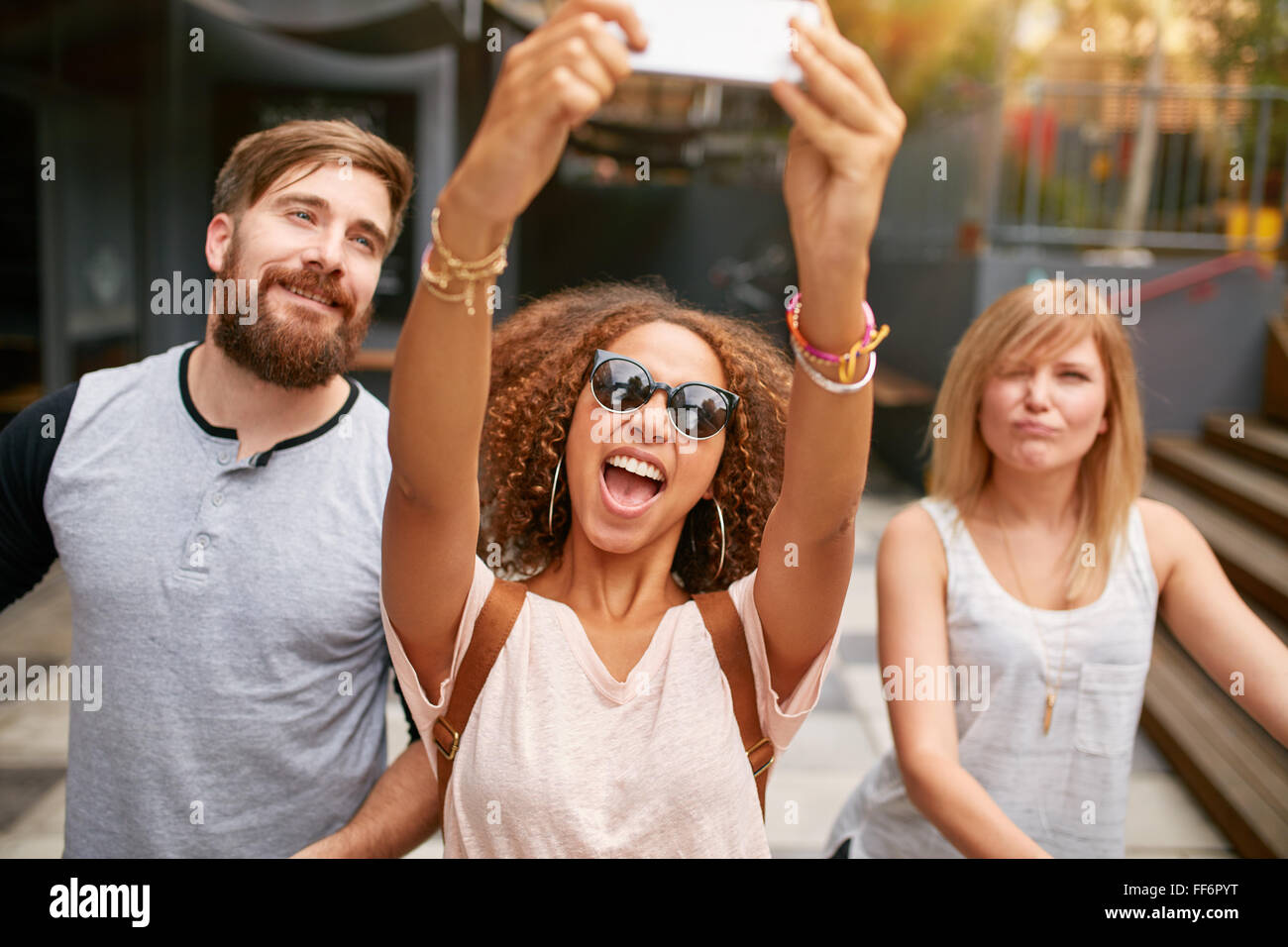 Excited donna giovane con amici prendendo un selfie sul suo smart phone. Donna africana tenendo selfie con il telefono cellulare. Foto Stock
