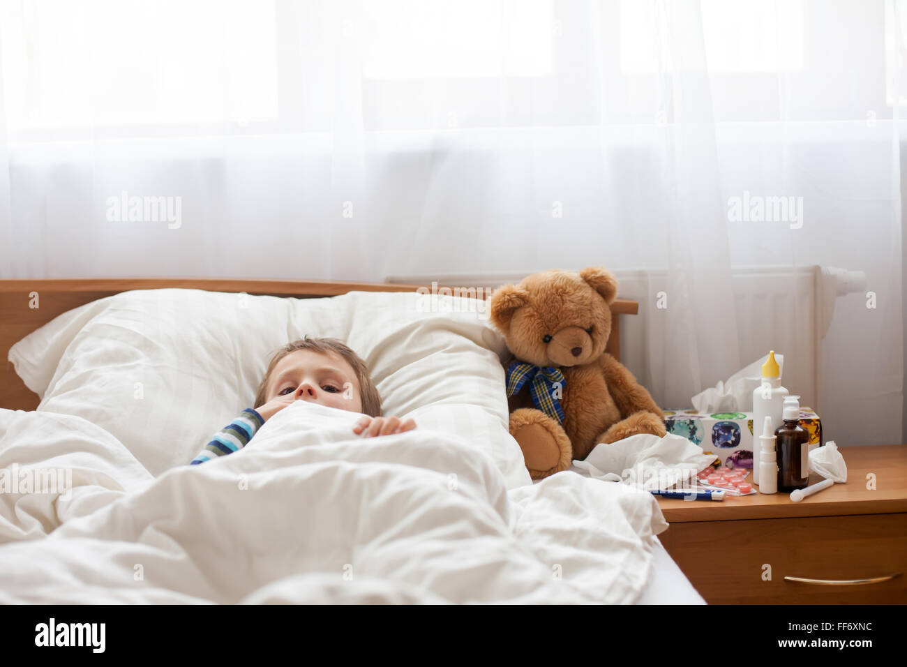 Bambino malato ragazzo disteso a letto con la febbre, in appoggio a casa Foto Stock