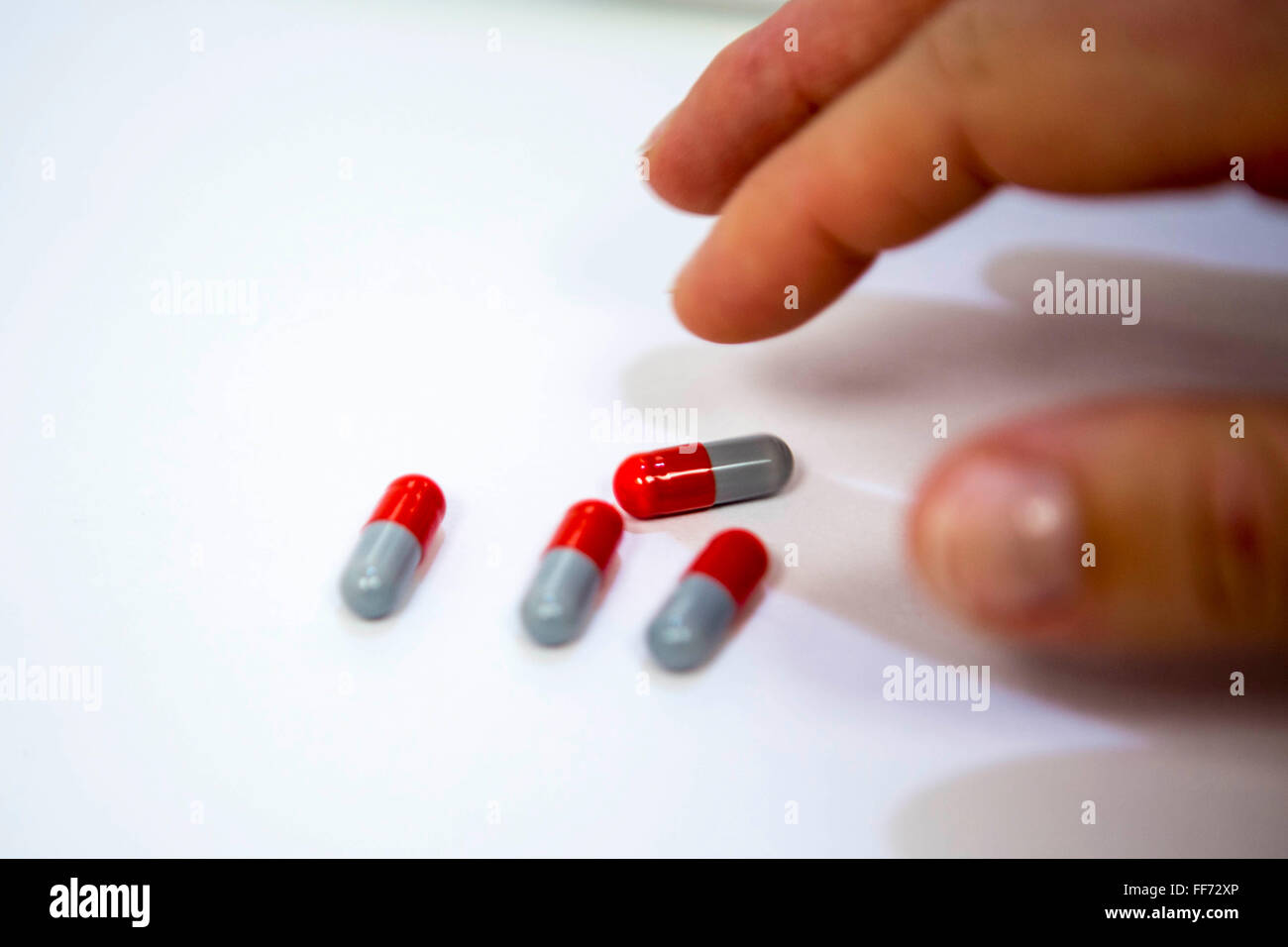 Una mano del paziente raggiunge per il loro quotidiano la tubercolosi farmaco in una tubercolosi clinica a Londra, Inghilterra, Regno Unito. Queste compresse sono l'antibiotico rifampicina che è la prima linea di trattamento per TB. Foto Stock