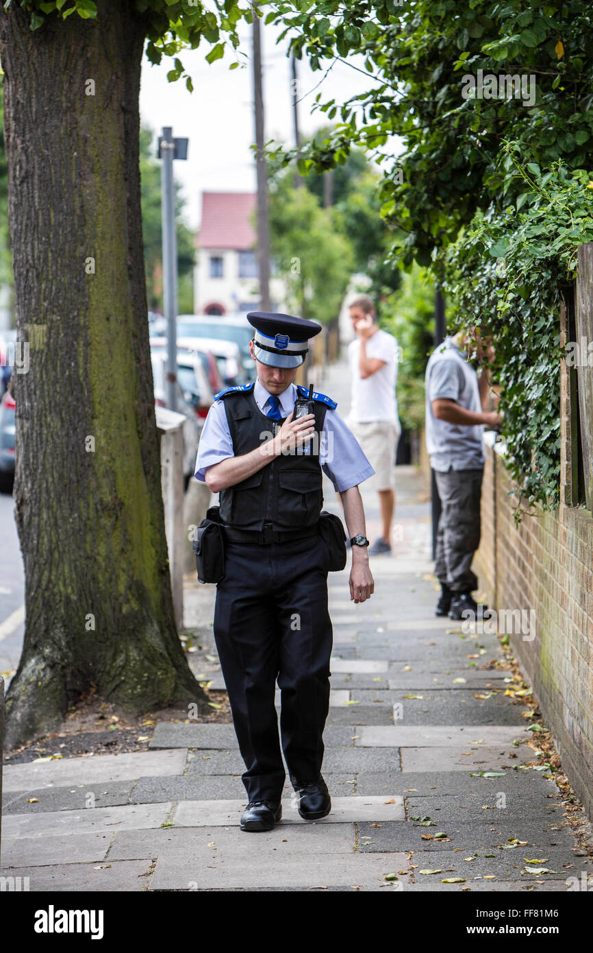 Una comunità di polizia Support Officer (PCSO) utilizza la sua radio mentre si cammina il battito nella città di Enfield, Greater London, Regno Unito. Foto Stock