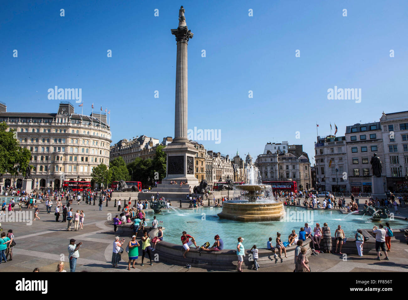 Turisti e londinesi godetevi una giornata d'estate attorno alle fontane di Trafalgar Square a Londra. Foto Stock