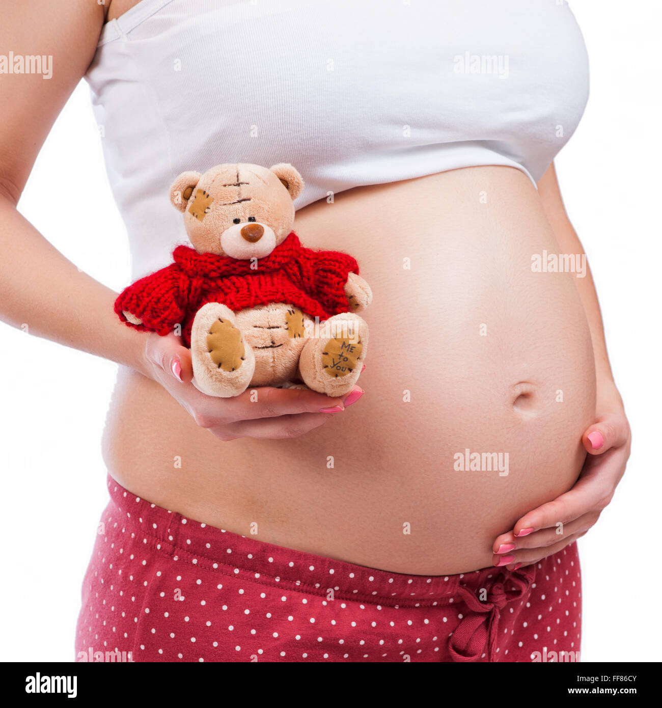 Donna incinta che mostra la sua pancia e tenendo un orsacchiotto Foto Stock