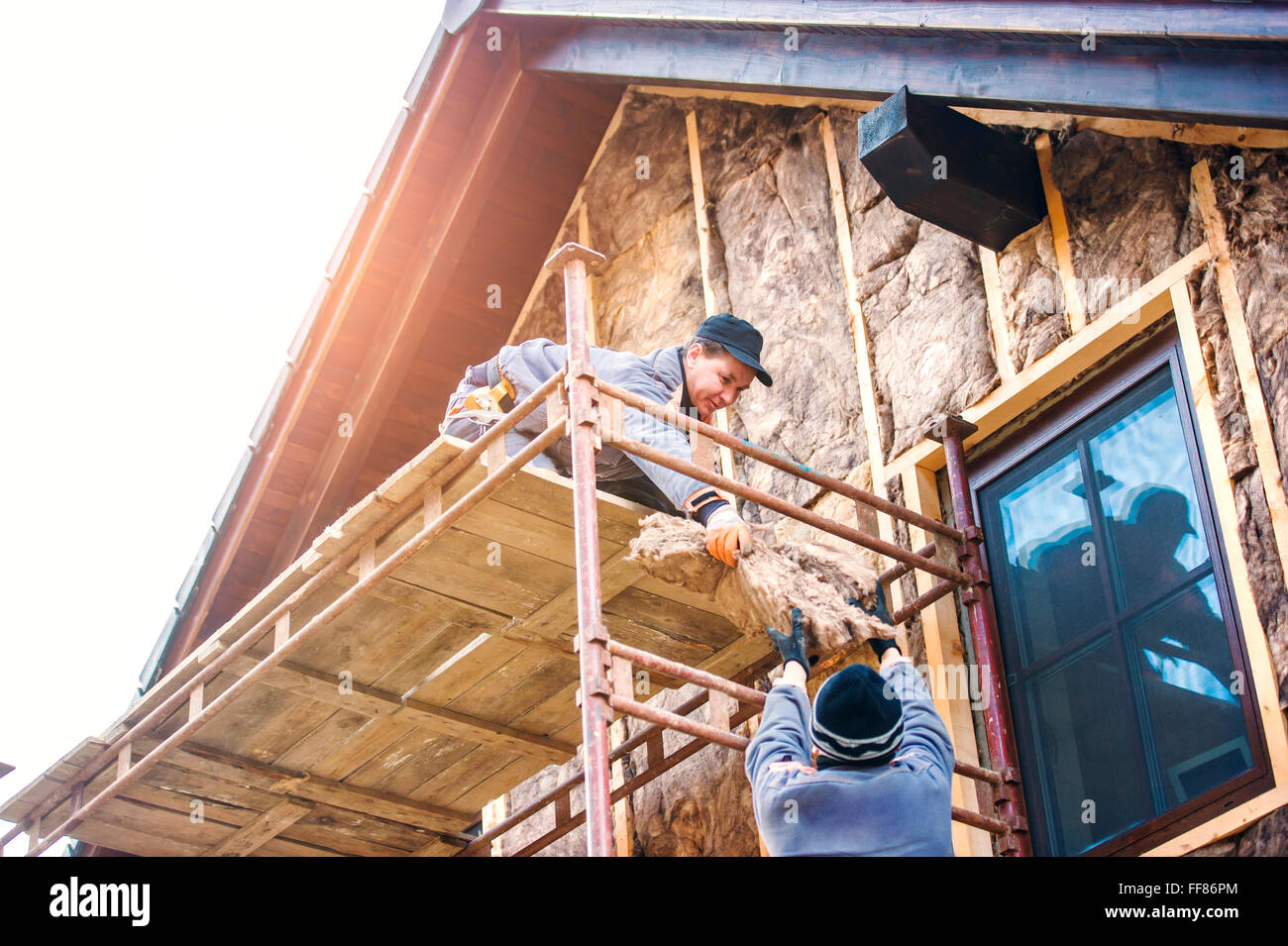 Lavoratori edili termicamente isolante di facciata della casa con lana di vetro. Foto Stock