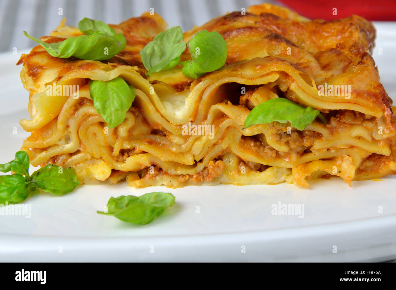 Strati di lasagne servite con foglie di basilico Foto Stock