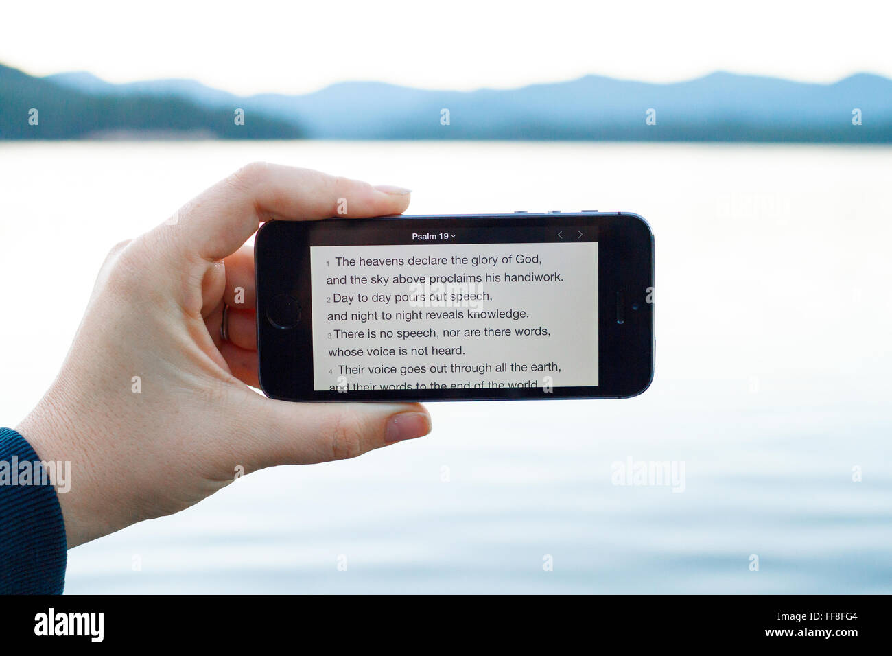 Smart phone al lago con il Salmo 19 versetti biblici sullo schermo. Foto Stock