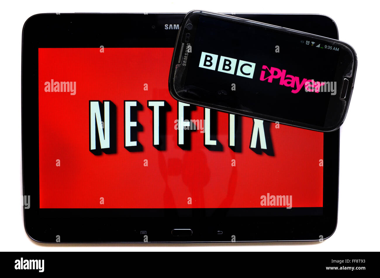 Il logo iPlayer su una schermata dello smartphone sulla parte superiore di un tablet visualizzando il logo di Netflix fotografati contro uno sfondo bianco. Foto Stock