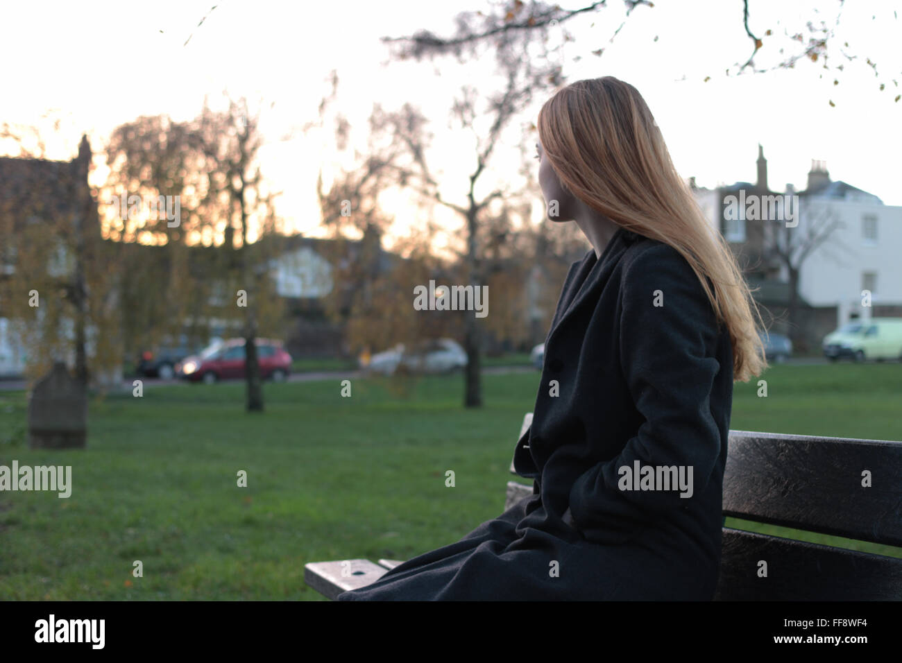 Giovani pensieroso donna seduta su una panchina guardando in lontananza. Foto Stock