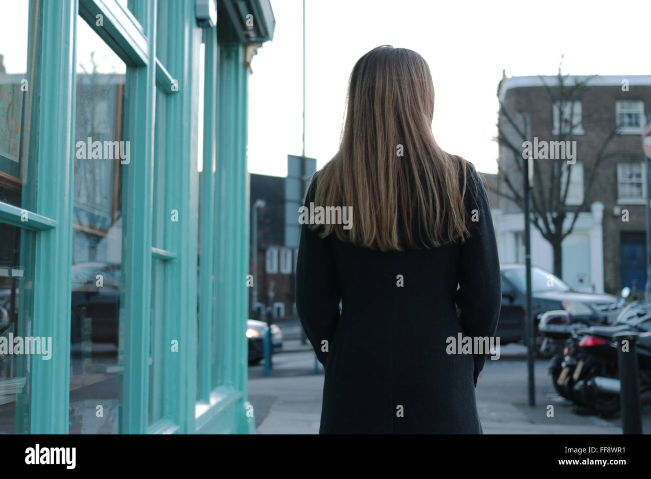 Vista posteriore di una giovane donna che cammina in una zona urbana. Foto Stock