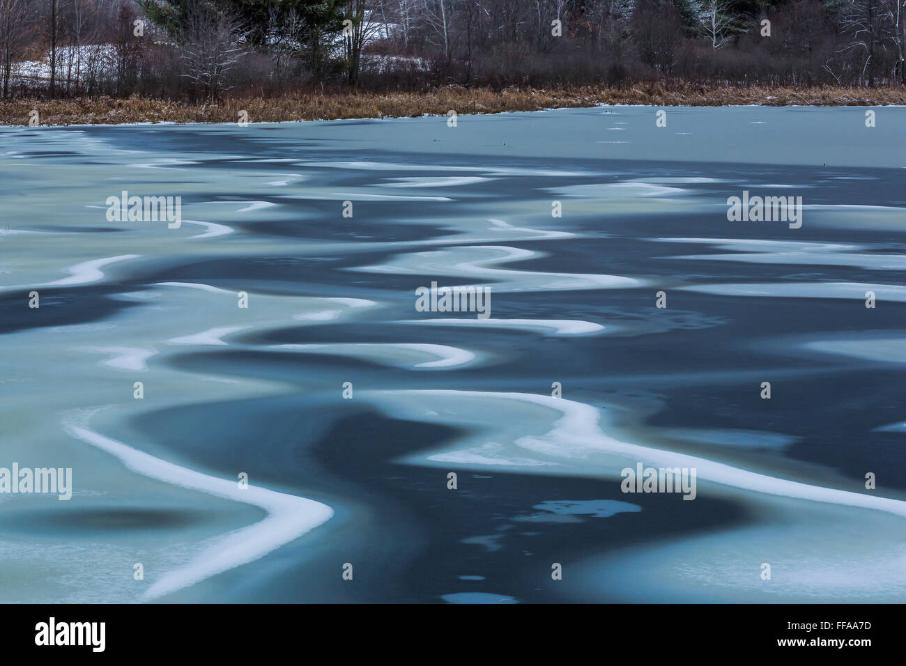Modelli di ghiaccio e neve in inverno presto su un laghetto nei pressi di Stanwood, Michigan, Stati Uniti d'America Foto Stock