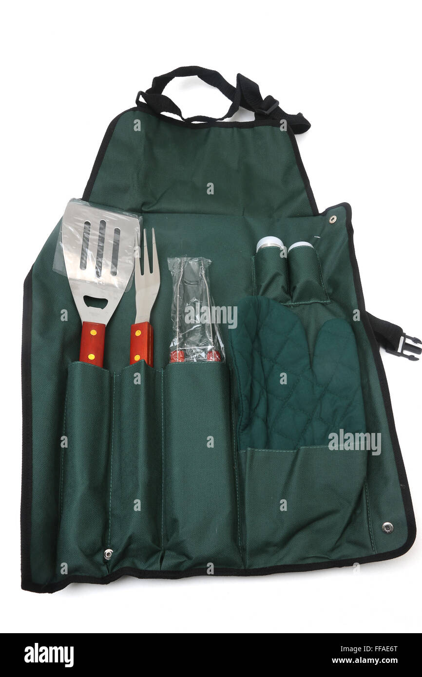 Barbecue utensili di cottura set- spatola, forcella, tenaglie, presina di sale e pepe il tutto avvolto nel grembiule Foto Stock