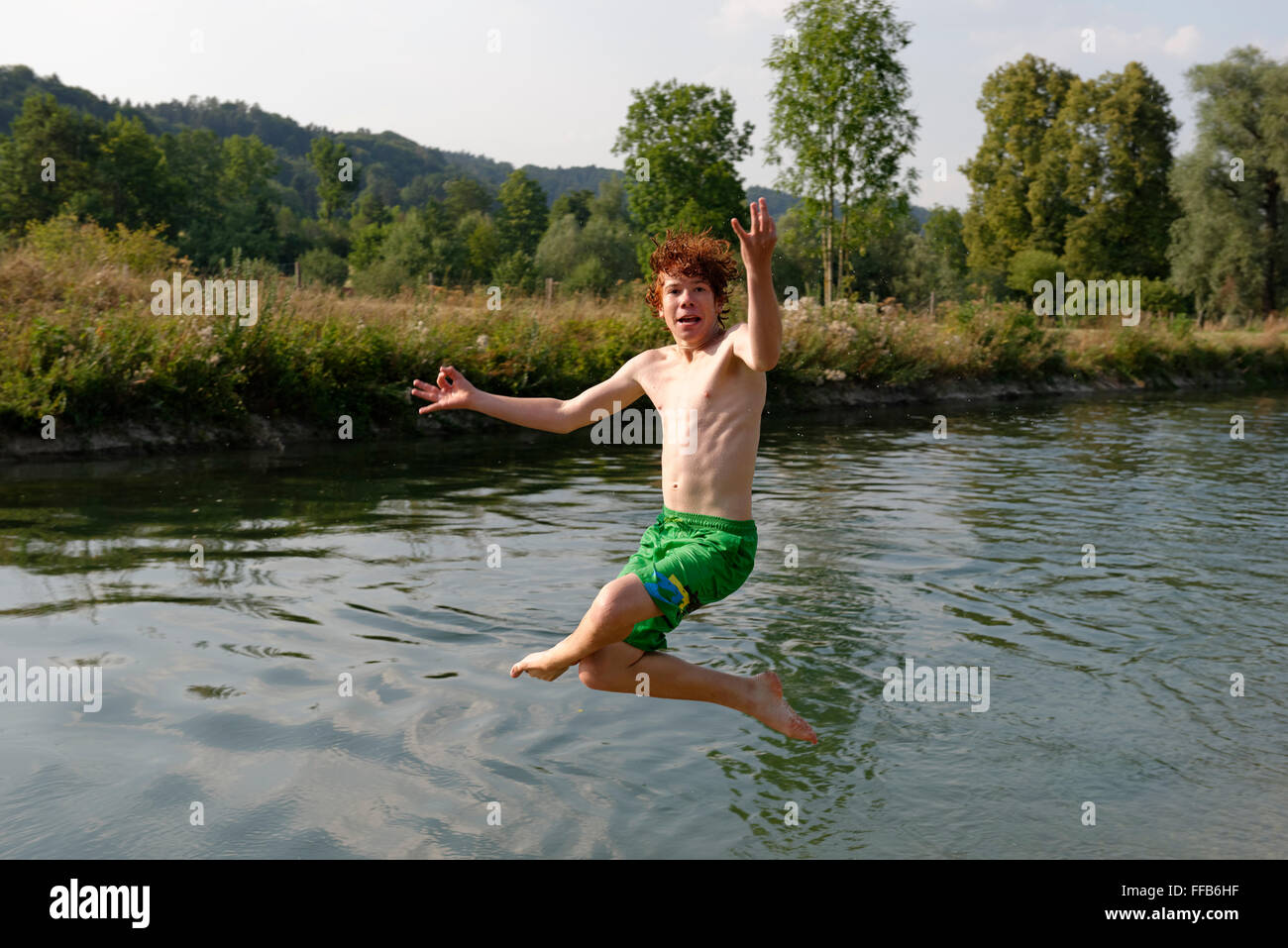 Ragazzo adolescente saltando nel fiume, Alta Baviera, Baviera, Germania Foto Stock