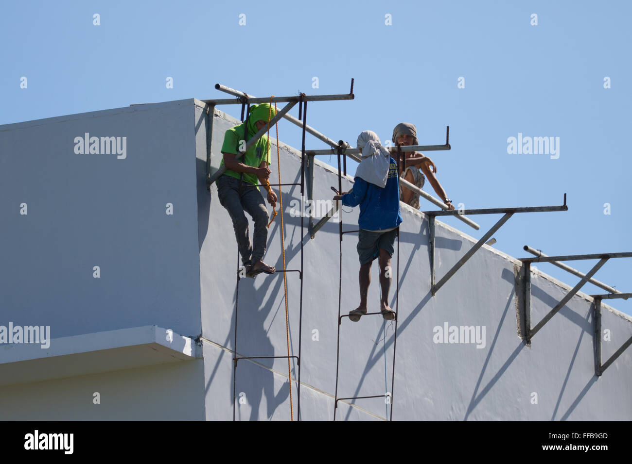 Una scena comune nelle Filippine edilizia - costruzione di lavoratori appendere precariamente dal ferro da stiro realizzato localmente e saldare le scale. Foto Stock