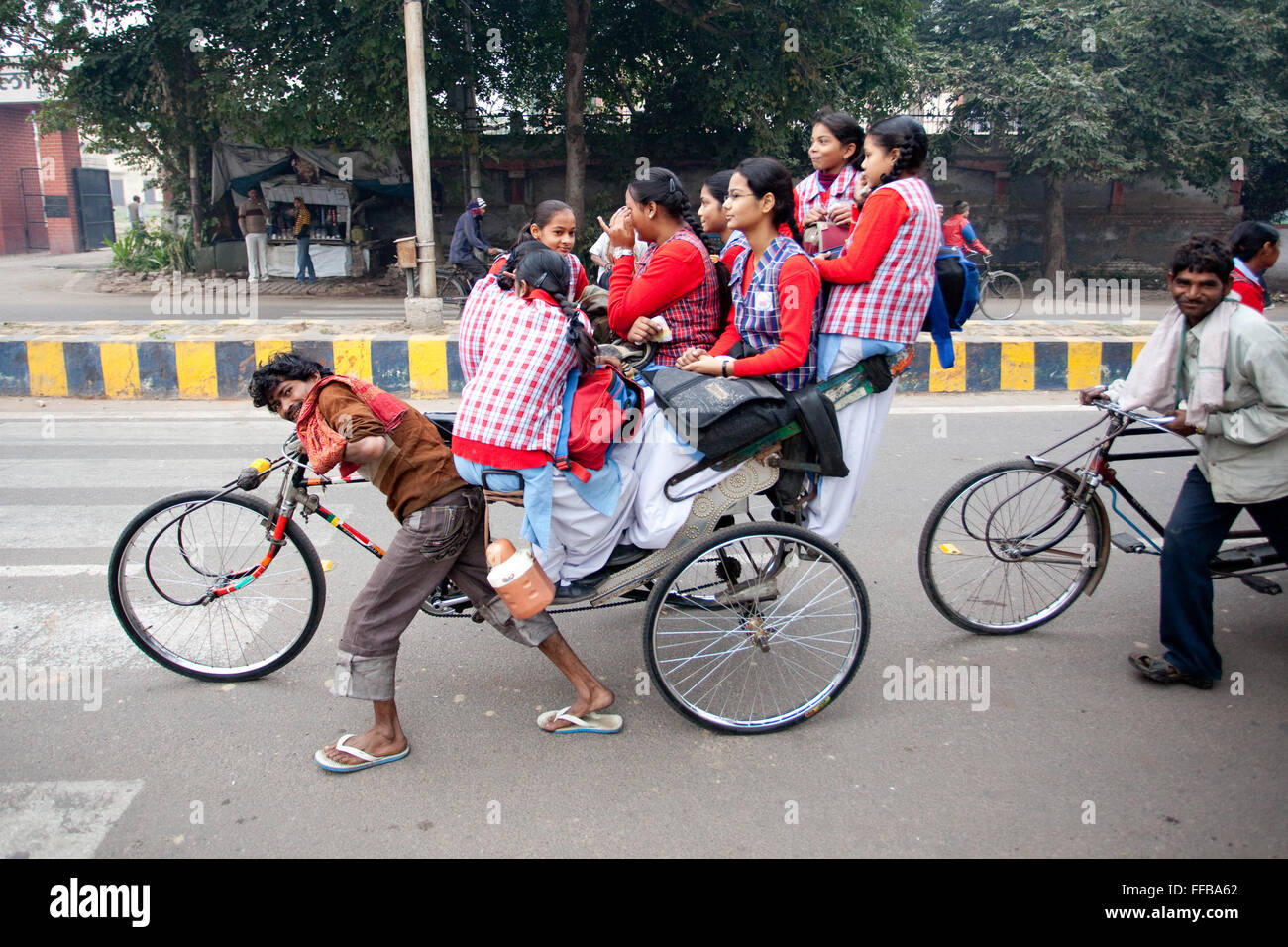 Il conducente di risciò che spinge una bicicletta piena di bambini della scuola Foto Stock