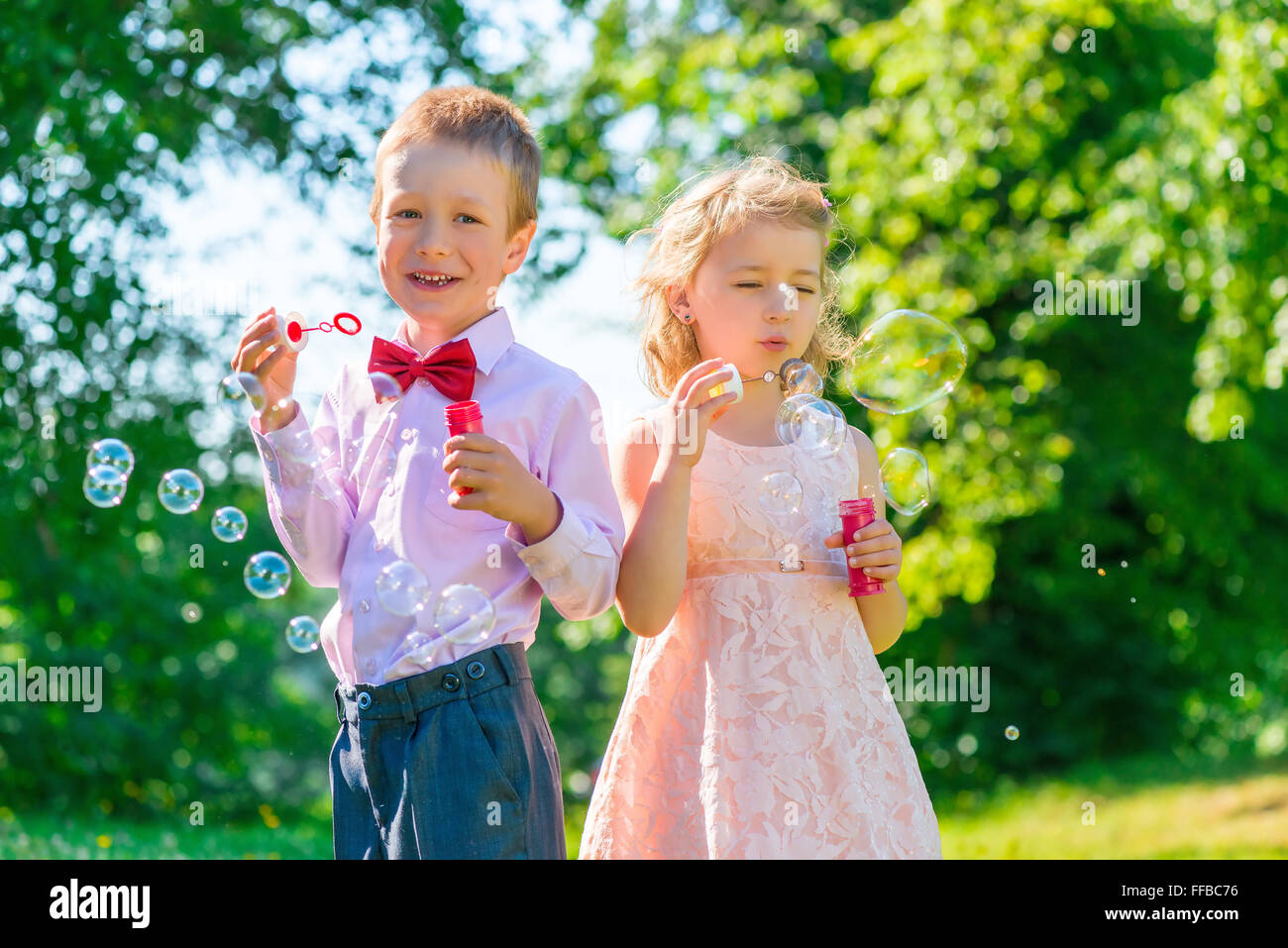 Fratello e Sorella di 6 anni nel parco con bolle di sapone Foto Stock