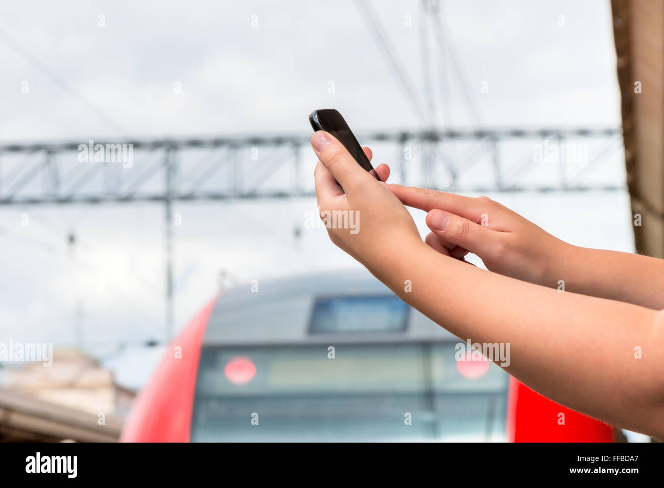 Le mani di close-up con un telefono mobile alla stazione ferroviaria Foto Stock