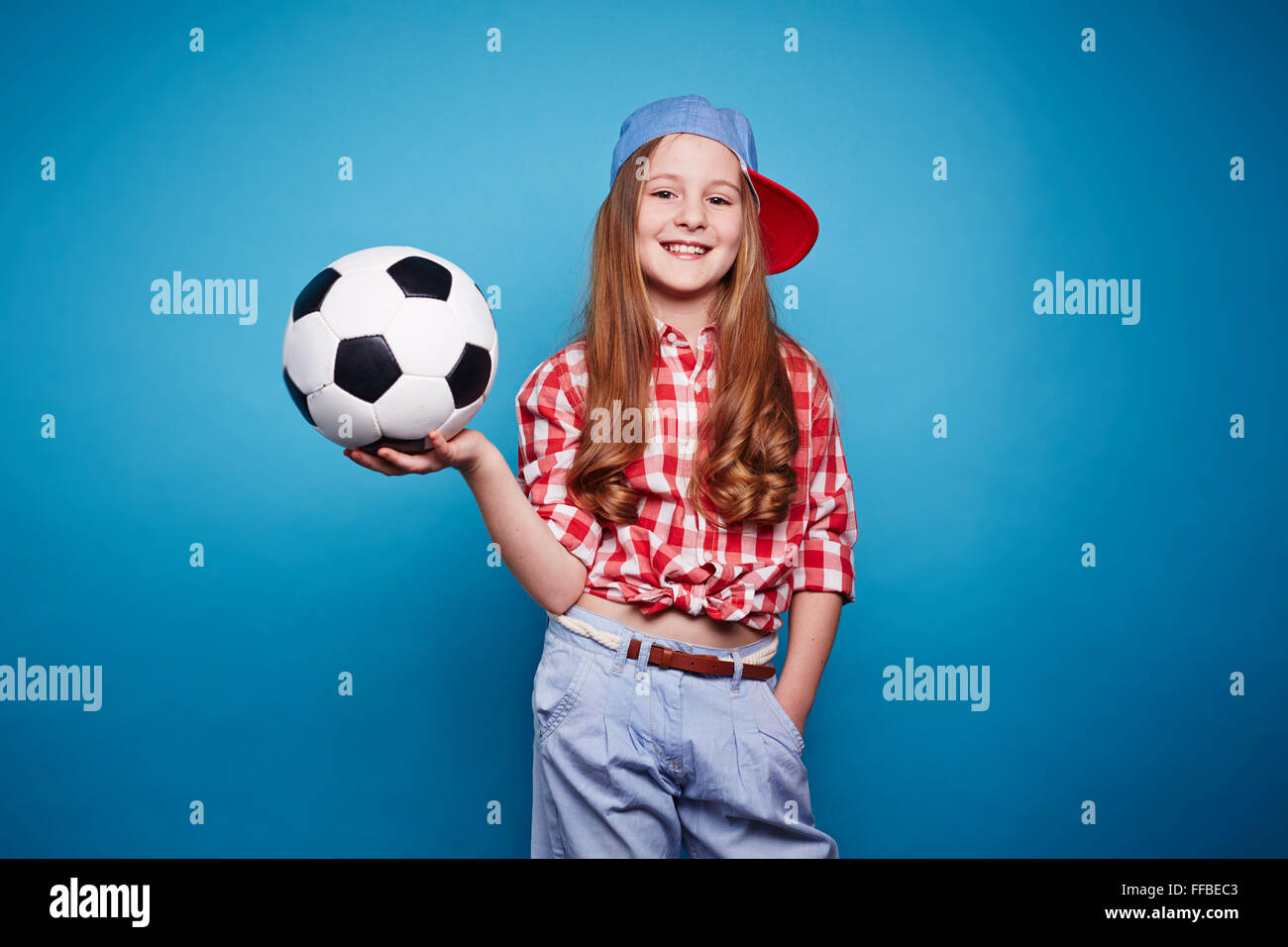Felice ragazza in informale tenendo palla per giocare a calcio Foto Stock
