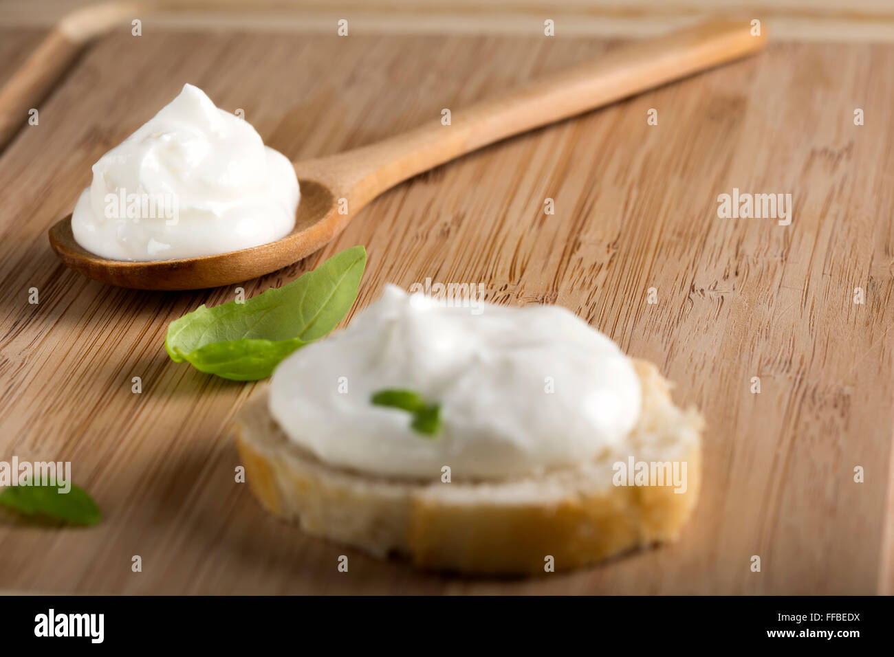 La crema fresca di formaggio in cucchiaio di legno su sfondo di legno Foto Stock