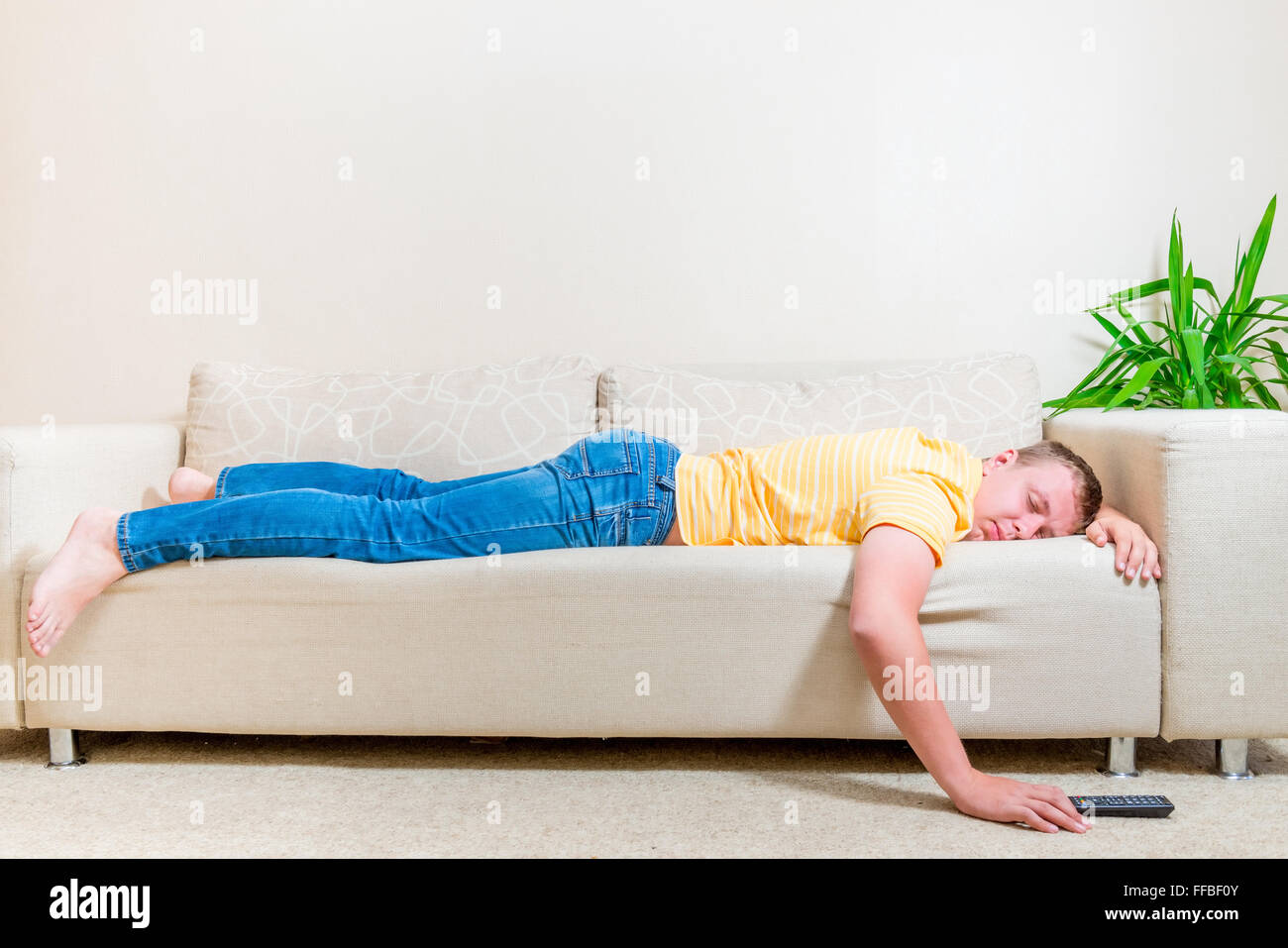 L uomo è caduto addormentato sul lettino dopo aver guardato la TV in salotto Foto Stock