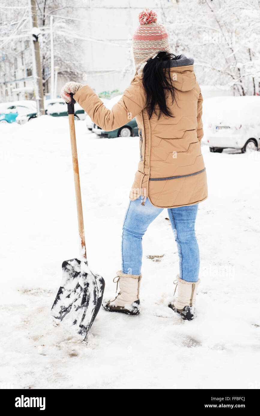 Retro della donna per prendersi una pausa da spalare la neve in parcheggio Foto Stock