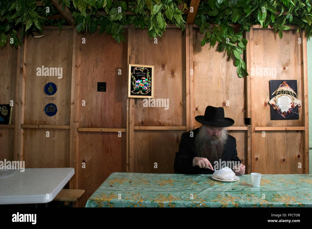 Rabbi Herschel Gluck mangiare un pasto da asporto nella sua Sukkah durante il festival di Sukkot, la festa dei tabernacoli. La vacanza commemora i quaranta anni di periodo durante il quale i figli d'Israele erano nel deserto. In onore dei figli di Israele nel deserto, gli uomini abitano in rifugi temporanei. Questo rifugio è chiamato un Sukkah ha almeno tre lati e un aprire parzialmente il tetto coperto di verde. Foto Stock