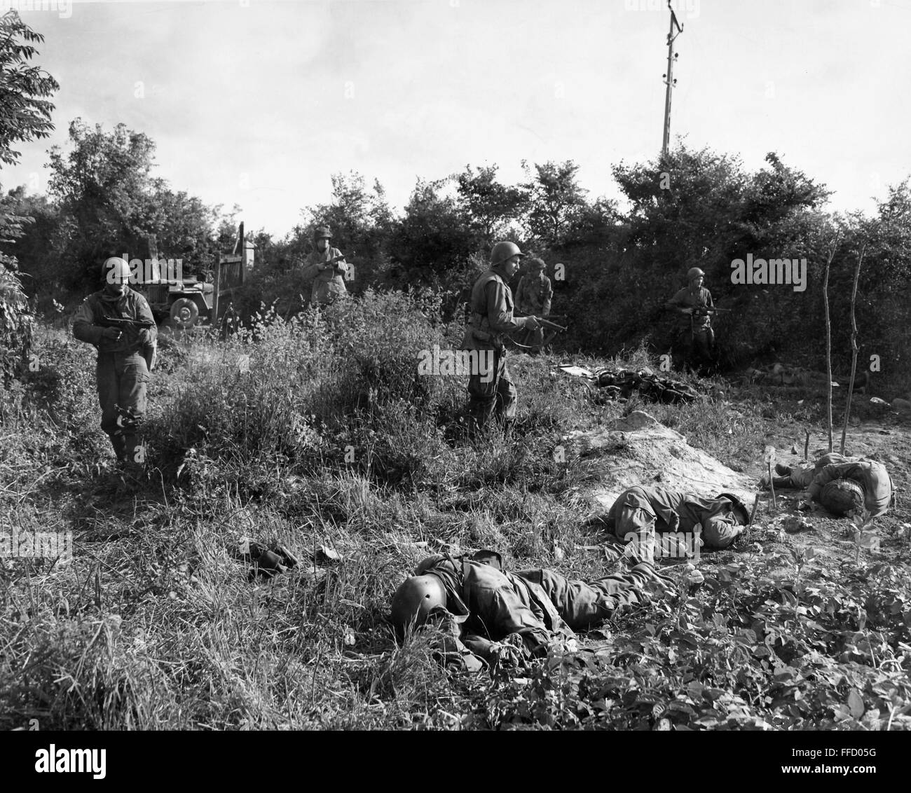 II Guerra Mondiale: Francia, 1944. /NAmerican paracadutisti muoversi attraverso un campo in Carentan, Francia, passando per i membri della loro propria unità ucciso dai cecchini tedesco. Fotografato il 14 giugno 1944. Foto Stock