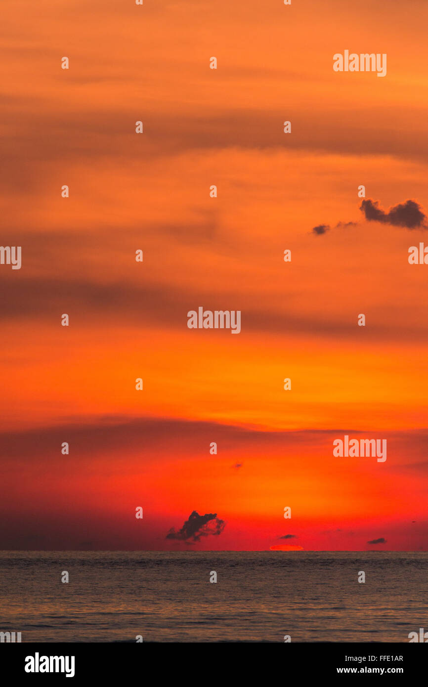 Profondo rosso tramonto quando il sole affonda sotto l'orizzonte off una spiaggia in western Sabah, Malesia Foto Stock