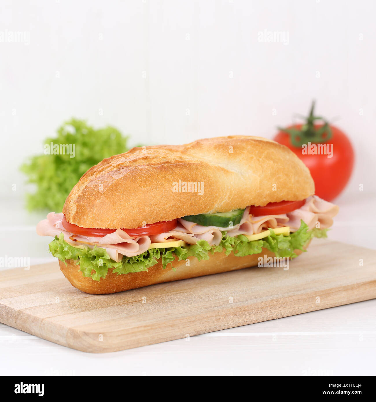 Mangiare sano sub deli sandwich baguette con prosciutto e formaggio, pomodori e lattuga per la prima colazione Foto Stock