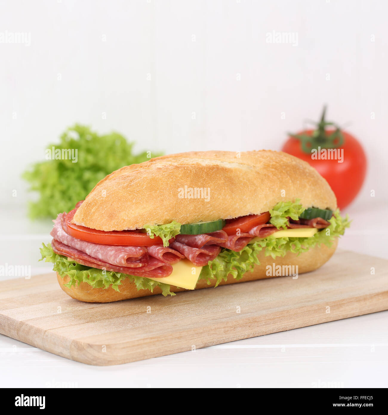 Mangiare sano sub deli sandwich baguette con salame prosciutto, formaggio, pomodori e lattuga per la prima colazione Foto Stock