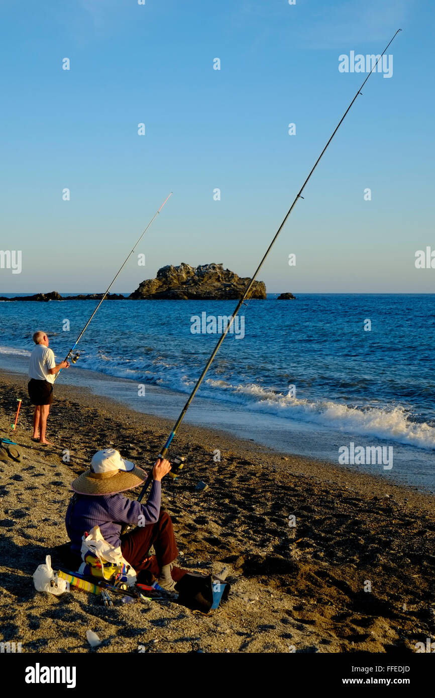 Due pescatori che pescano dalla spiaggia mentre il sole sta scendendo. Almuñécar, Provincia di Granada, Andalusia. Spagna Foto Stock