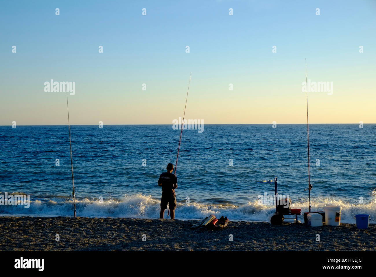 Lone pescatore dalla spiaggia come il sole scende. Almuñécar, Granada, Andalusia. Spagna Foto Stock