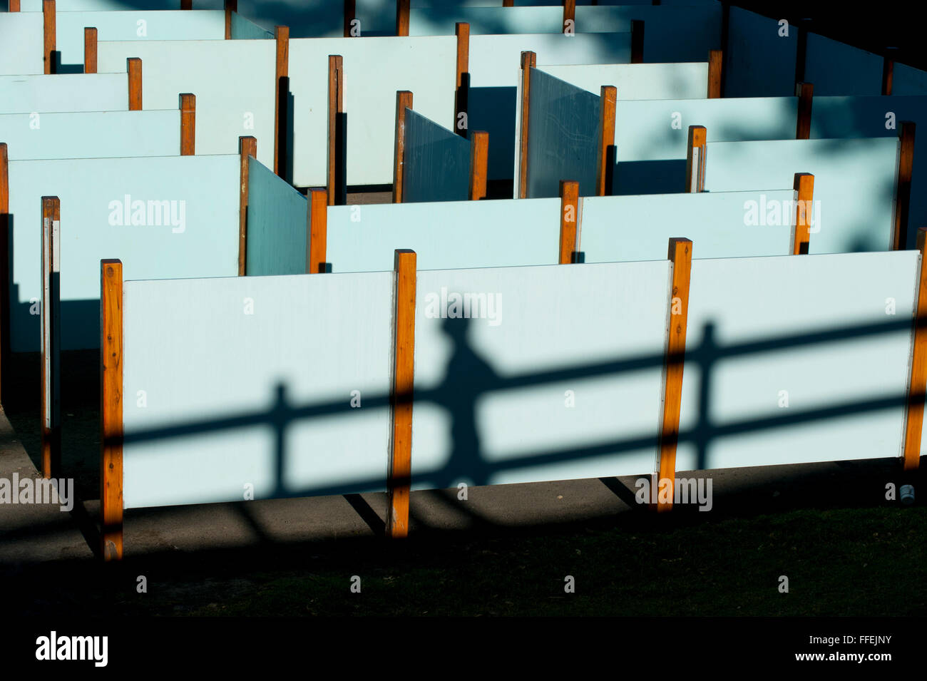 Pedoni e corridori le loro ombre contro un labirinto di schermate di bianco in un parco in Australia. Foto Stock