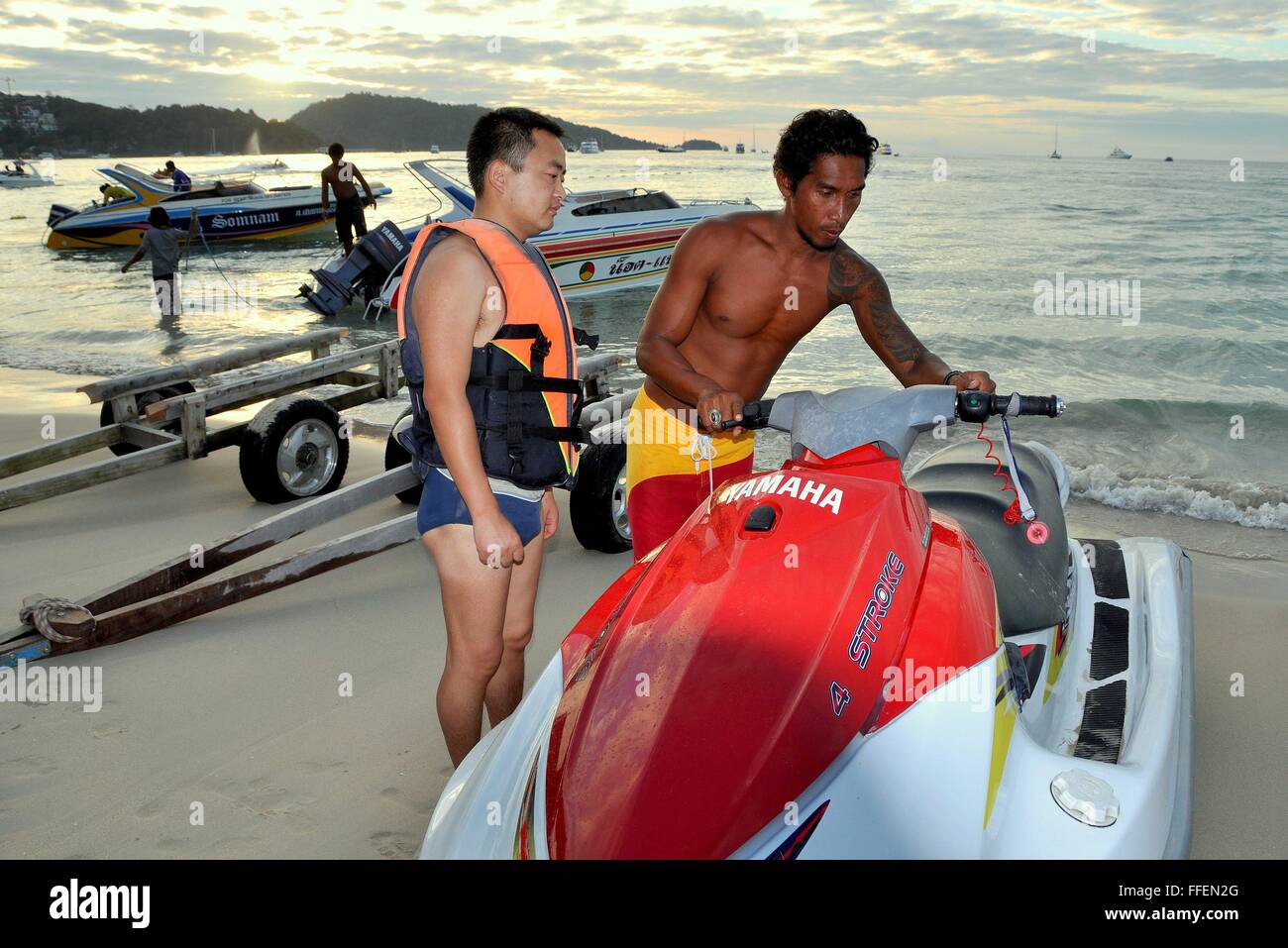 Phuket, Tailandia : Thai man (destra) dà istruzioni su come far funzionare un jet ski barca per un turista cinese a Patong Beach Foto Stock