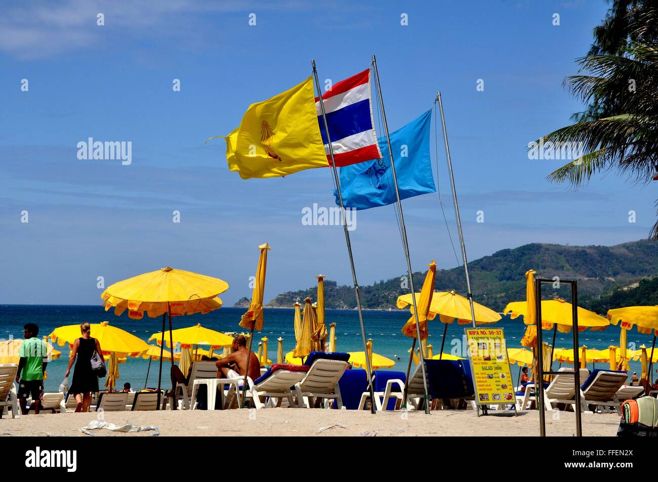 Phuket, Tailandia: Colore giallo brillante ombrelloni ombra beachgoers a Patong Beach Foto Stock