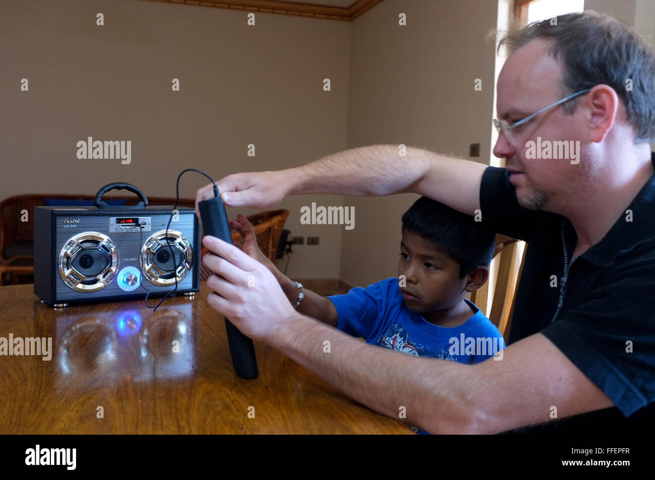 Cochabamba Bolivia. Matura caucasica padre aiuta il suo latino ha adottato un ragazzo a collegare un Apple iPad stereo con altoparlanti portatili Foto Stock