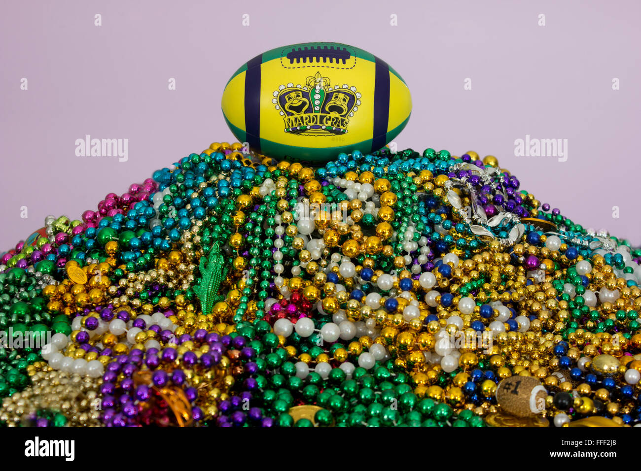 Mardi Gras maschere e re la corona stampato su un football americano, arroccato sulla cima di un enorme pila di Mardi Gras perline. Foto Stock