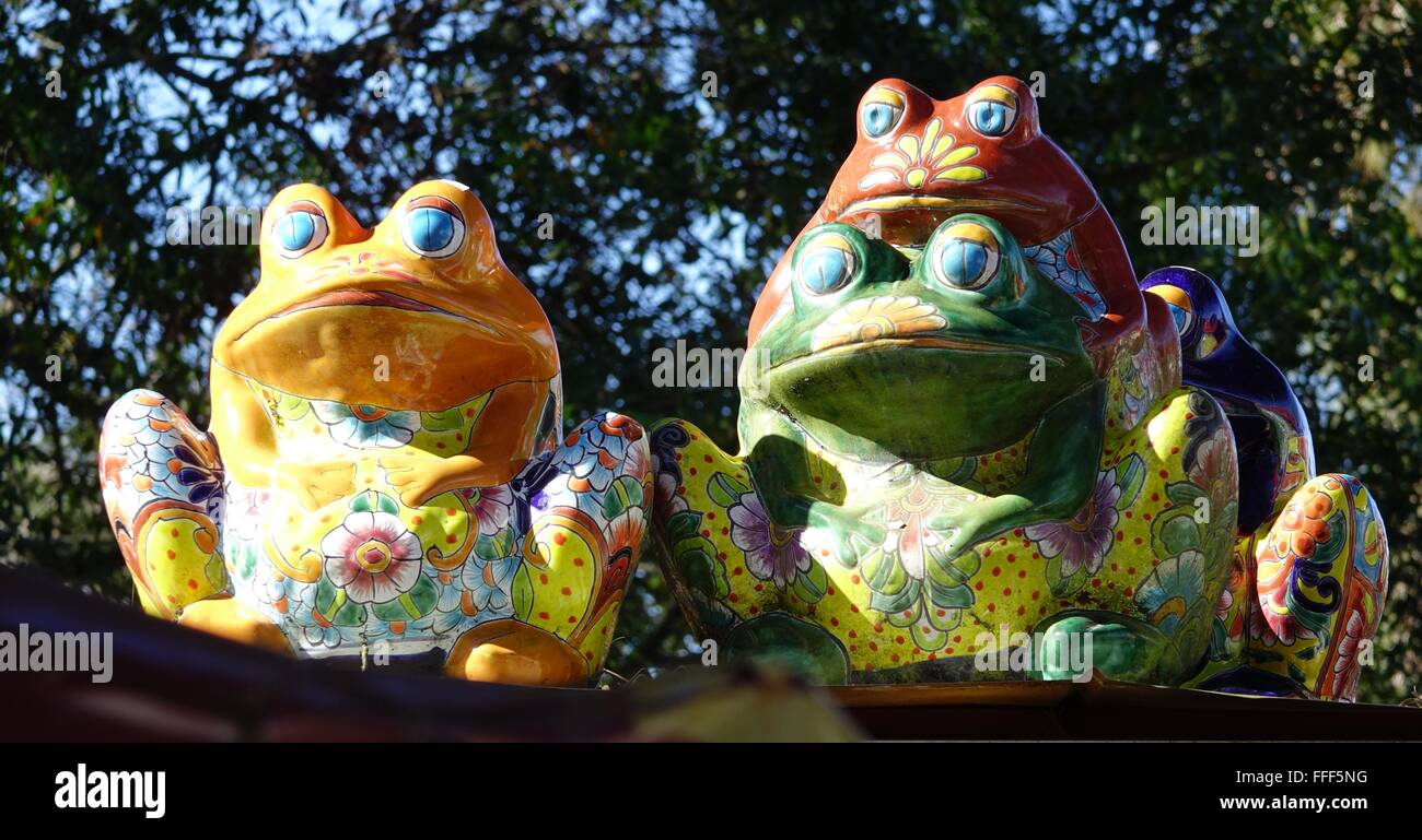 Colorate rane in ceramica seduto su una recinzione Foto Stock